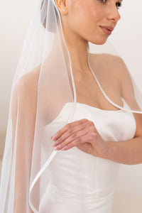 Bride wearing satin ribbon ivory wedding veil